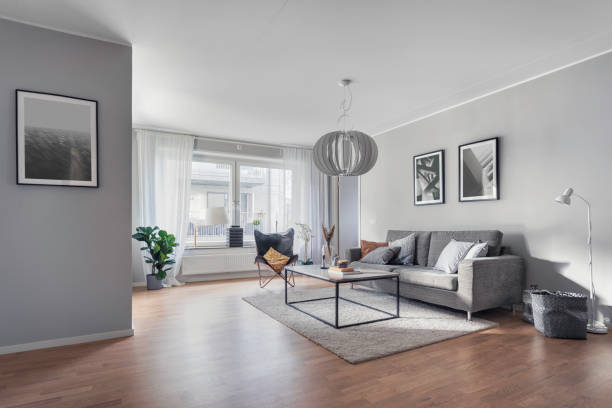 Modern living room with gray couch, decorative art, and natural light from large windows.