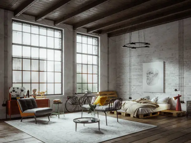 Bright, industrial-style bedroom with large windows, a cozy seating area, and wooden pallet furniture.