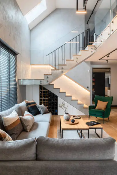 Modern living room with a stylish staircase, large windows, and contemporary decor.