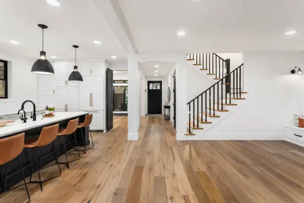 Modern kitchen and dining area featuring a large island, stylish bar stools, and a staircase leading to the upper level.