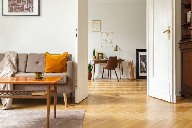Cozy living area with a plush sofa, wooden coffee table, and home office space in the background.