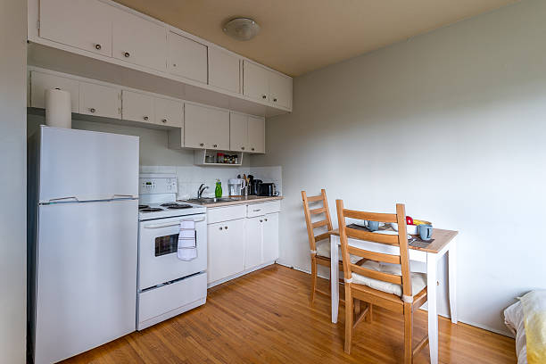 Cozy kitchen and dining area featuring white cabinets, a refrigerator, and wooden flooring.