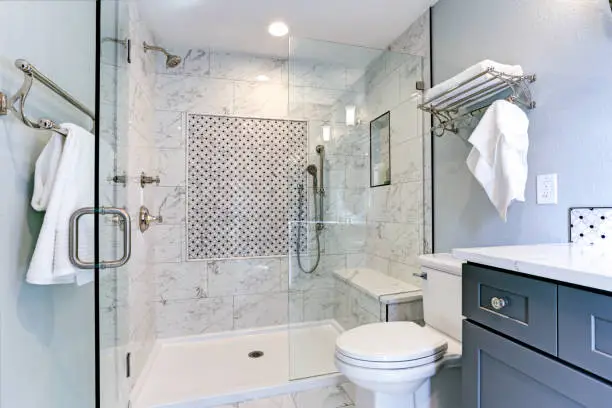 Modern bathroom featuring a glass shower, marble tiles, and elegant fixtures.