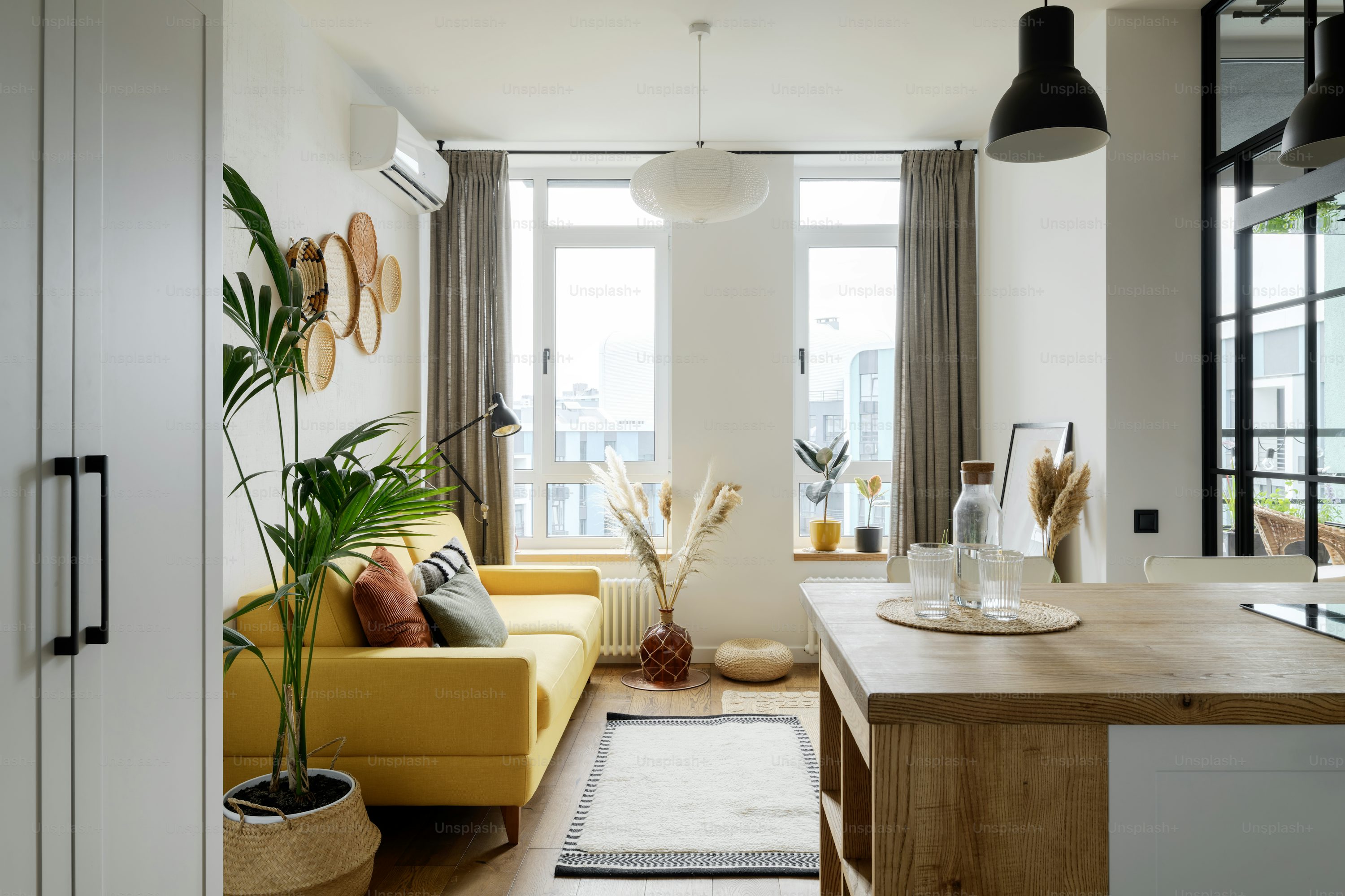 Cozy modern living room featuring a yellow sofa, plants, and large windows.
