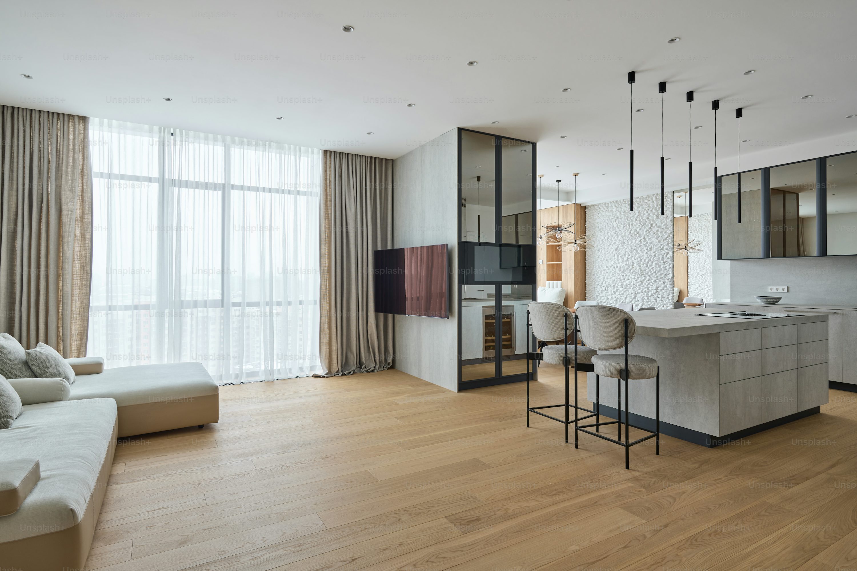 Modern open-concept living space featuring a sleek kitchen with bar seating and large windows.