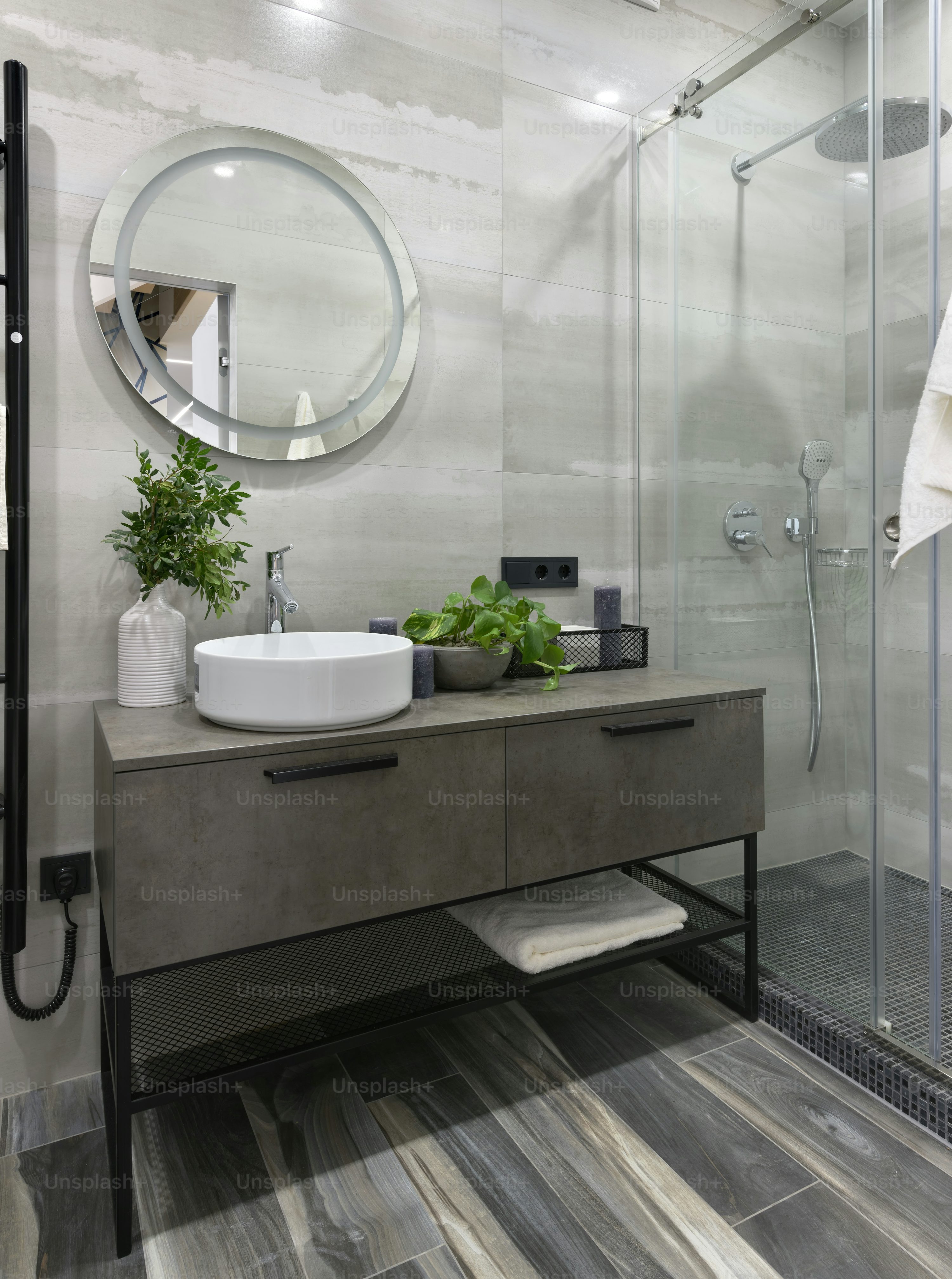Modern bathroom featuring a sleek vanity, circular mirror, and a spacious glass shower.