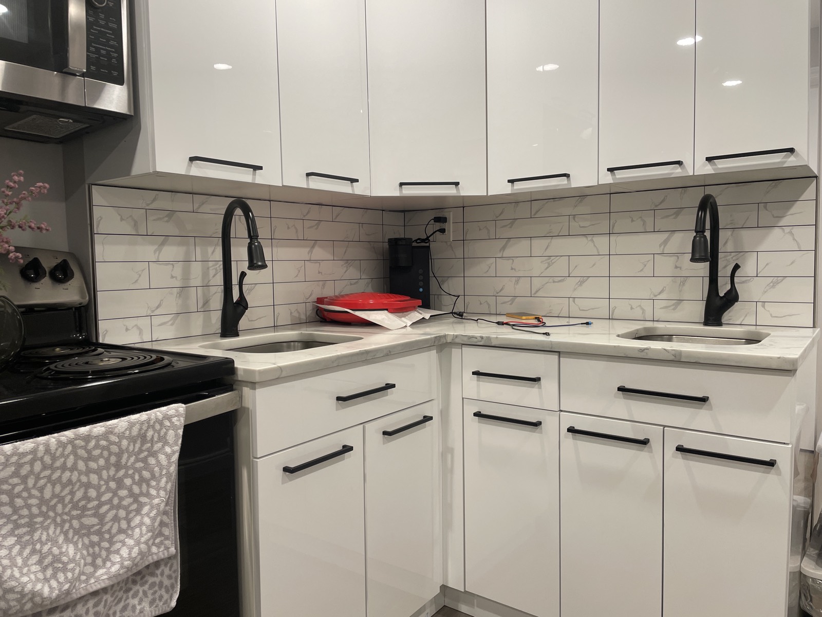 Modern kitchen with white cabinets, black hardware, and dual sinks.